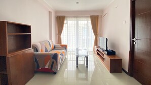 A living room with a sofa, a TV, a glass table, and a door.