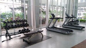 A gym with treadmills, dumbbells, and a bench. - Stylish and Comfy Studio at Casa De Parco Apartment (Pagedangan)