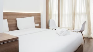 A hotel room with a large bed, two chairs, a nightstand, and a mirror. - Stylish and Comfy Studio at Casa De Parco Apartment (Pagedangan)