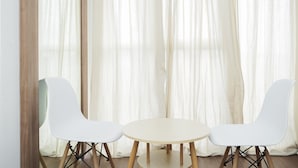 A room with two white chairs and a round table, with sheer curtains in the background. - Stylish and Comfy Studio at Casa De Parco Apartment (Pagedangan)