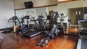 Une salle de sport équipée de divers appareils d’exercice, notamment des tapis de course, des vélos d’appartement et des appareils de musculation elliptique.