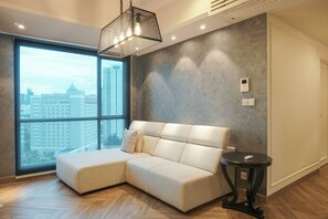 A modern living room with a sectional sofa, a round side table, and a large window offering a city view.