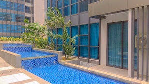 A modern building with a swimming pool, surrounded by greenery and large windows. - Luxurious 2BR Apartment at Casa Grande Residence (Jakarta)