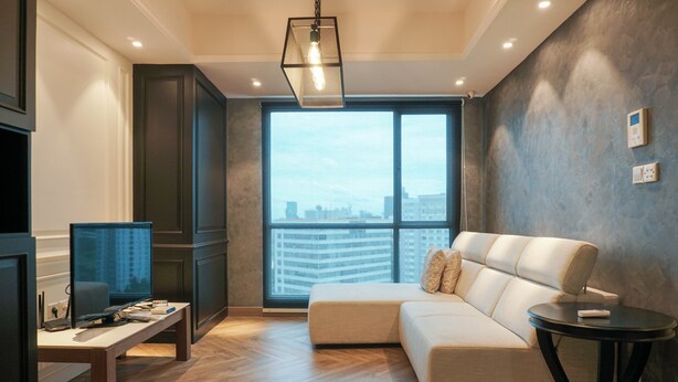 A modern living room with a sectional sofa, a flat-screen TV, and a large window offering a city view. - Luxurious 2BR Apartment at Casa Grande Residence (Jakarta)