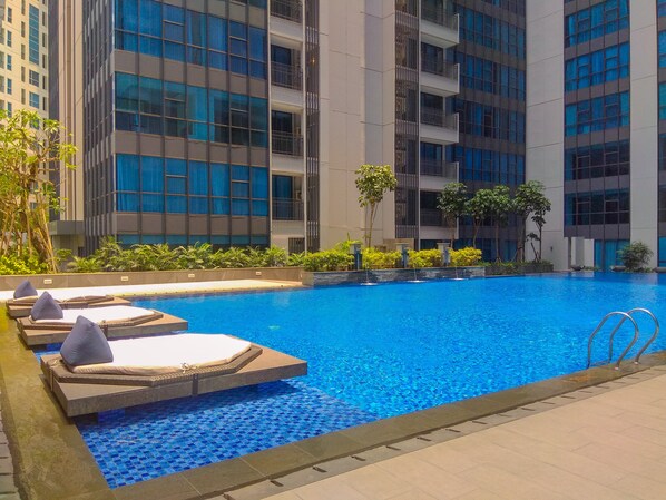 A swimming pool with lounge chairs and a view of modern buildings.