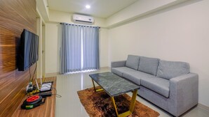 Una sala de estar moderna con un sofá gris, una mesa de centro de vidrio y un televisor de pantalla plana montado en una pared de madera.