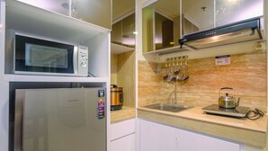 Cocina compacta con microondas, refrigerador y hervidor sobre la encimera.
