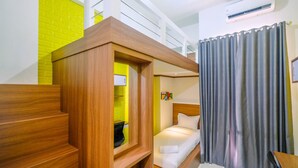 Habitación pequeña con una litera, una mesita y cortina de ducha.