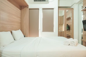 A hotel room with a bed, a wardrobe, and a television.
