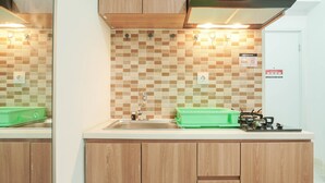 Une cuisine avec des meubles en bois, un plan de travail carrelé, un évier et une cuisinière à gaz.