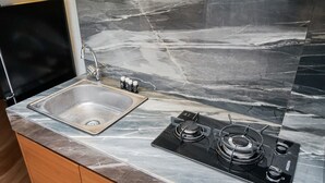 Una cocina con pileta, estufa y encimera de mármol.