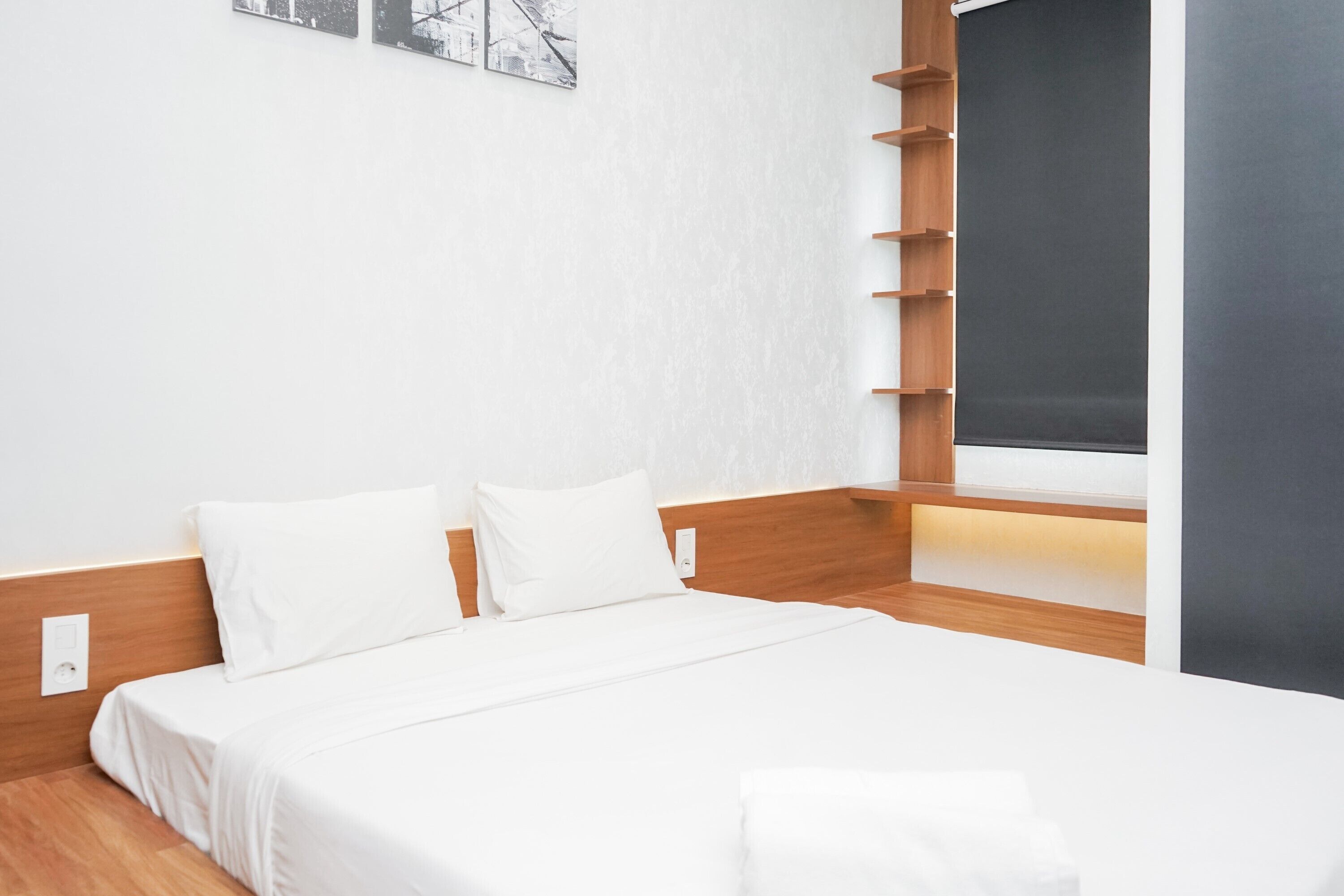 Una habitación de hotel moderna con una cama bien hecha, un cabecero de madera y un ventanal con vistas.
