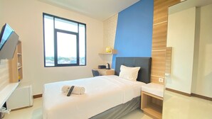 A modern hotel room with a bed, a desk, a chair, a TV, and a large window.