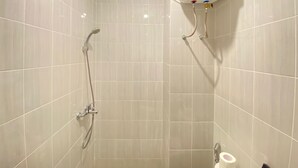 A shower with a handheld showerhead and a wall-mounted faucet.