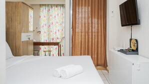 Una habitación de hotel con cama, escritorio, televisor y armario.