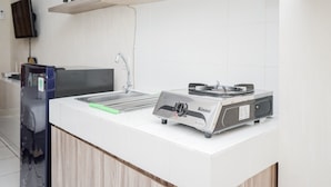 Una cocina con encimera blanca, una cocina por inducción Rinnai, un lavamanos y un armario de madera.