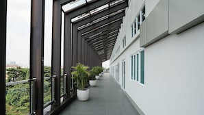 Un couloir au design architectural moderne, agrémenté d’une série de grandes fenêtres et de plantes en pot le long du passage.