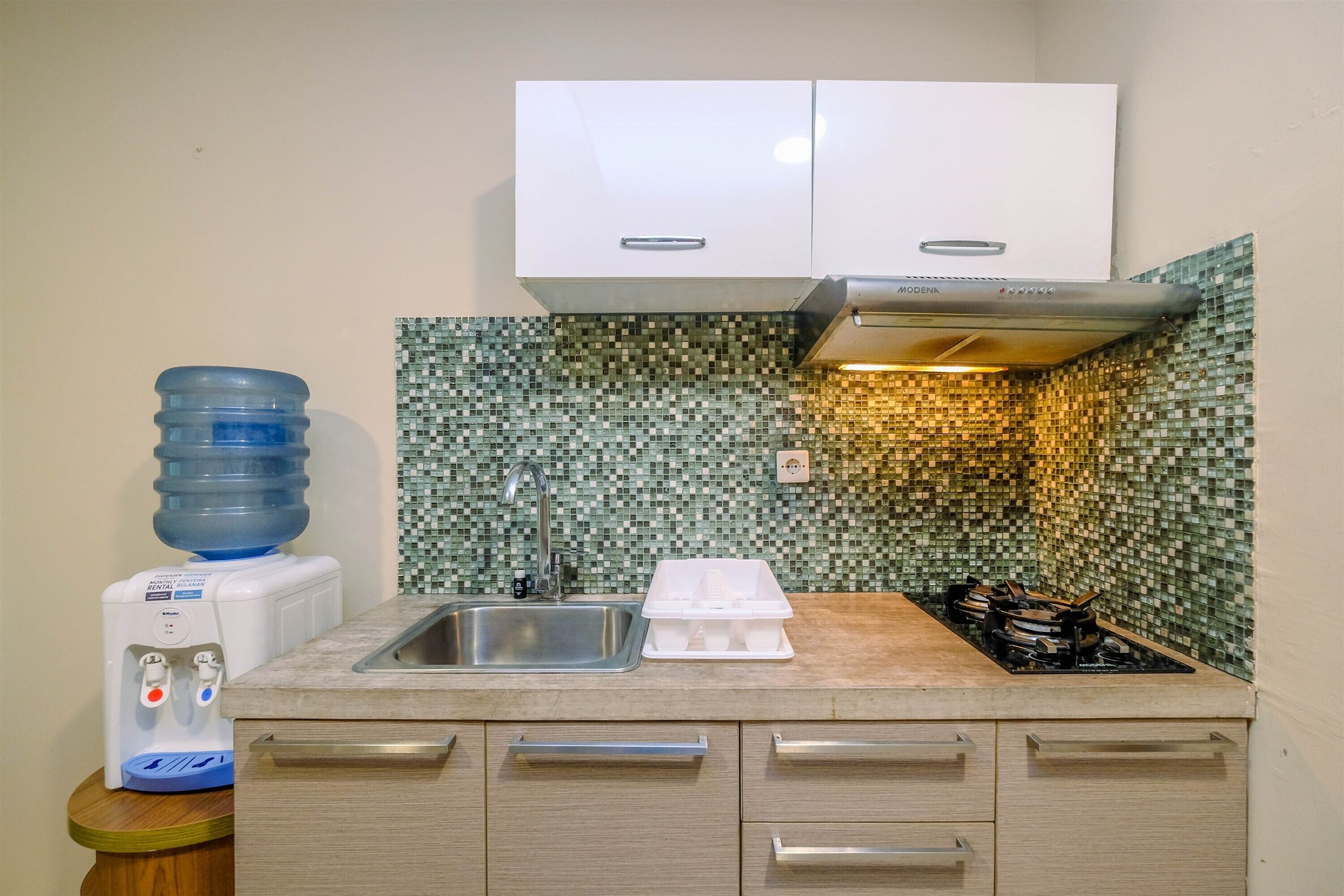 A kitchen with a water dispenser, a sink, and a stove.