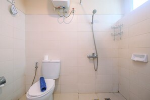 A small, clean bathroom with a toilet, a shower, and a towel rack.