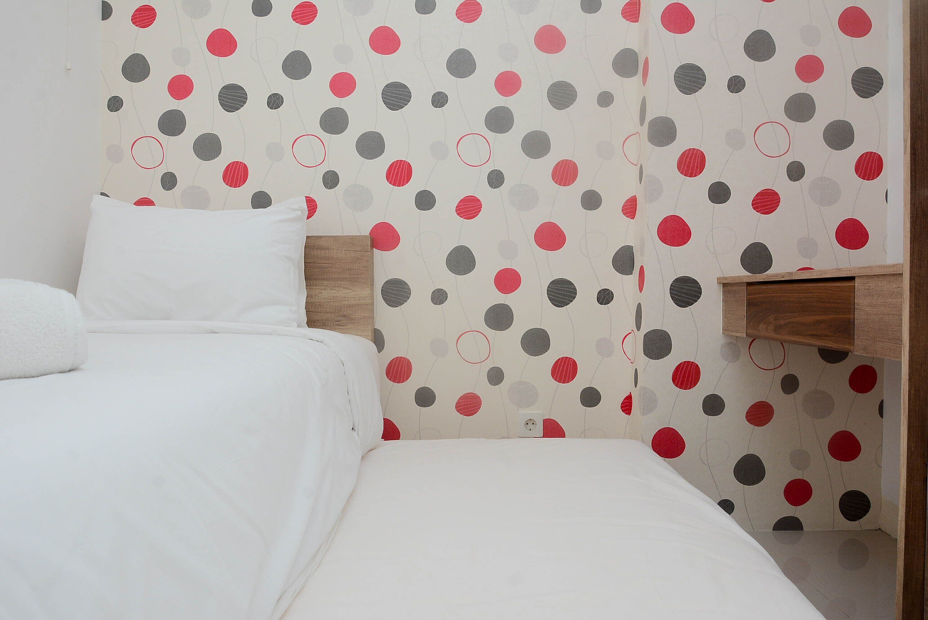 A bedroom with a bed, a bedside table, and a wall with a polka dot pattern.