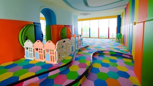 A brightly colored play area with hexagonal patterned flooring, colorful walls, and playful architectural elements. - Great Location Studio at Menteng Park Apartment (Jakarta)