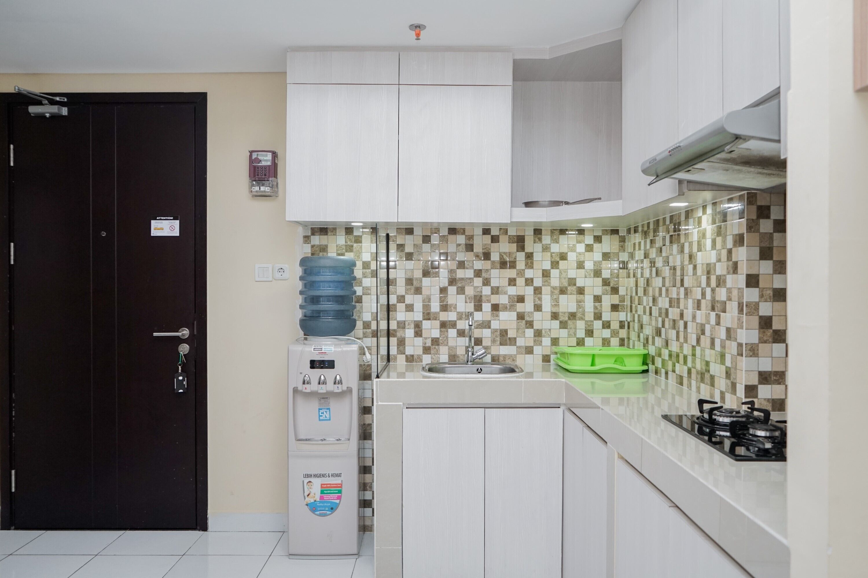 A compact kitchen with a water dispenser, a sink, and a gas stove.