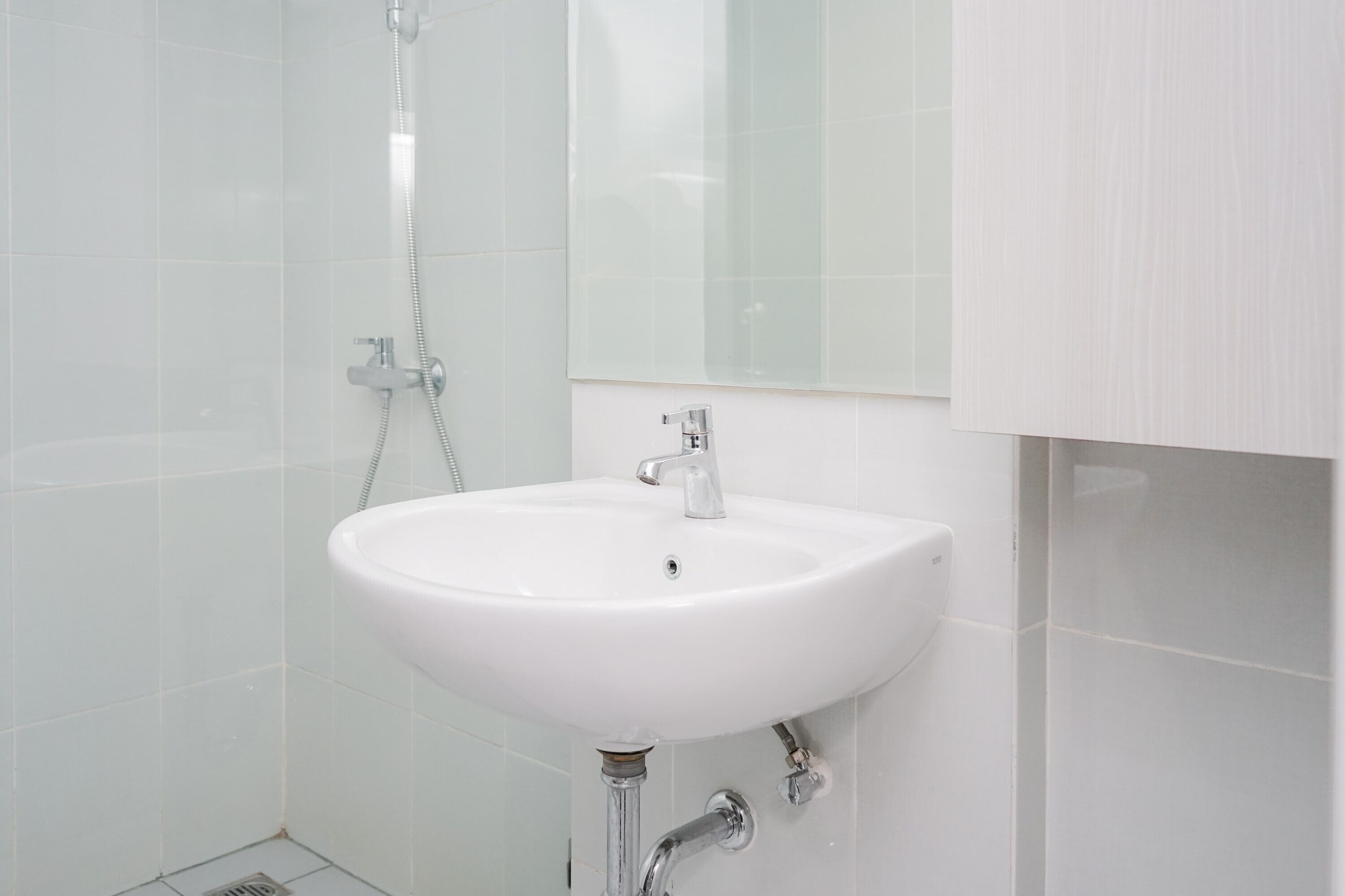 A bathroom with a white sink, a mirror, and a shower.