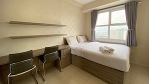 Una habitación de hotel con cama, dos sillas, un escritorio y una ventana con cortinas.