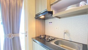 Una kitchenette compacta con estufa a gas, un lavamanos y una pequeña encimera.