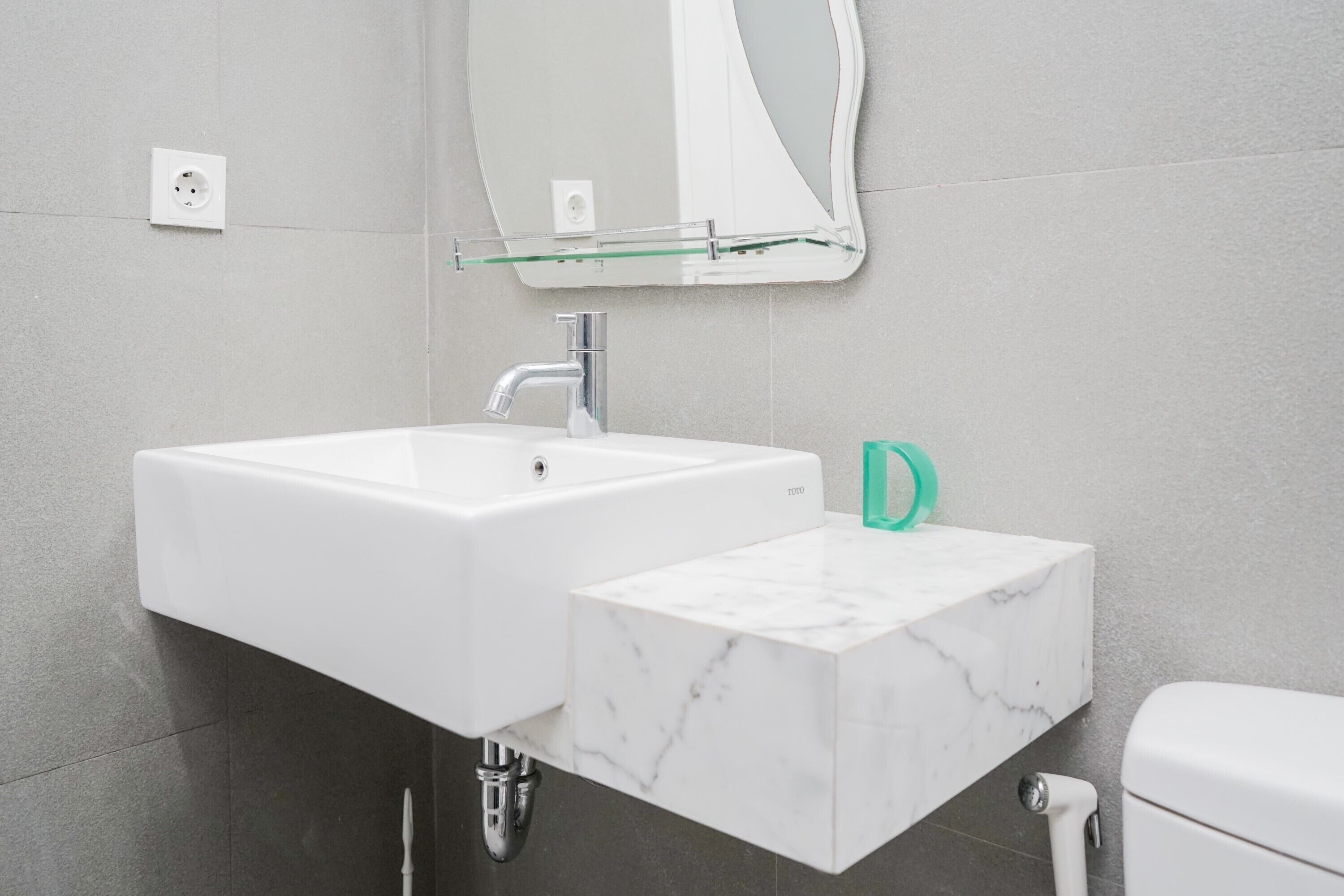 Une salle de bain avec un lavabo blanc, un miroir et des toilettes.
