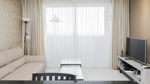 A living room with a sofa, a small table, a TV, and a lamp.