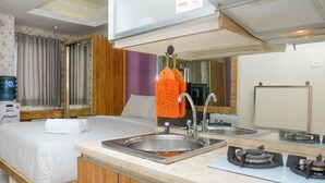 A hotel room with a bed, a bathroom, a sink, and a mirror. - Homey Studio Pakubuwono Terrace Apartment (Jakarta)