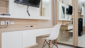 A modern kitchen with a built-in TV, white cabinets, and a white chair. - Simply Strategic and Comfy Studio Paramount Skyline Apartment (Gading Serpong)