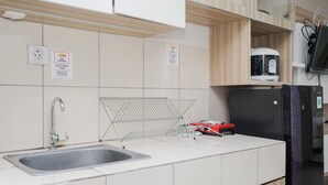 A kitchen with a sink, a coffee machine, and a refrigerator. - Simply Strategic and Comfy Studio Paramount Skyline Apartment (Gading Serpong)