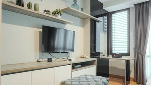 Een moderne woonkamer met een flatscreen televisie, een bank, een salontafel en een eethoek met televisie en een klein tafeltje.