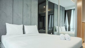 Een moderne hotelkamer met een groot bed, een spiegel en uitzicht op het interieur door een glazen deur.
