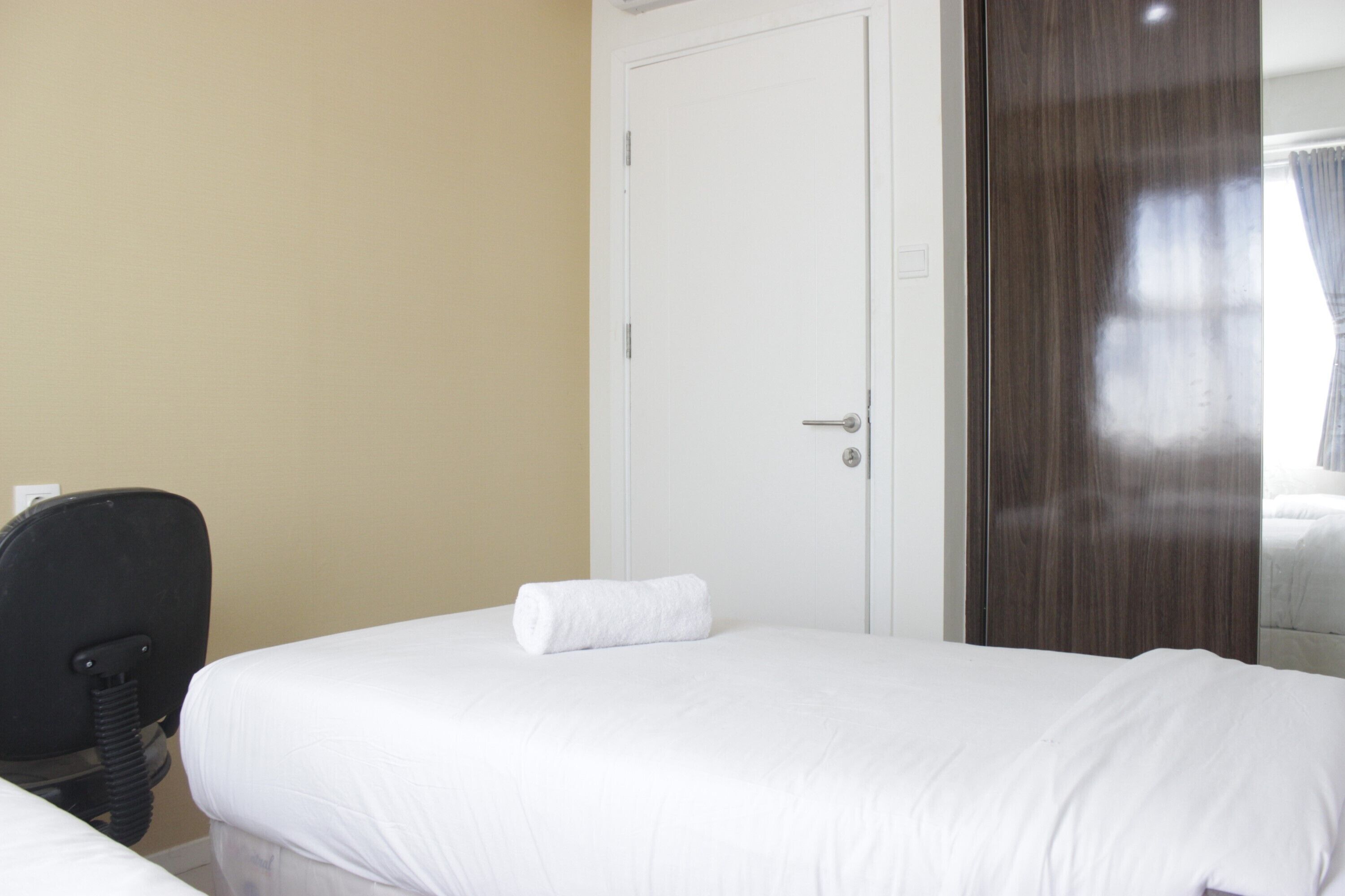 Una habitación de hotel con dos camas, una puerta blanca y un armario de madera.
