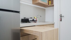 A modern kitchen with a built-in gas stove, a sink, and wooden cabinetry. - Fully Furnished with Cozy Design Studio Poris 88 Apartment (Tangerang)