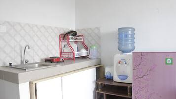 Una cocina con un lavamanos, un escurreplatos, un dispensador de agua y un refrigerador.