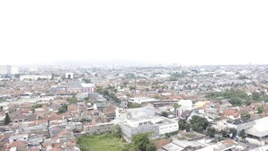 Une zone urbaine densément peuplée, avec de nombreux bâtiments, dont une grande structure à plusieurs étages dotée d’un toit plat et un bâtiment plus petit, à un seul étage, avec un toit en pente.