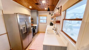 A kitchen with a stainless steel refrigerator, a built-in oven, a sink, and wooden flooring. - Adorable Ocean View 3 Bed/1 Bath Cottage Sleeps 8 steps to the beach (Ocean Isle Beach)