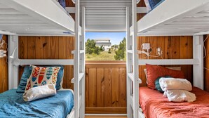 A bunk bed room with a view of a house and greenery outside. - Adorable Ocean View 3 Bed/1 Bath Cottage Sleeps 8 steps to the beach (Ocean Isle Beach)