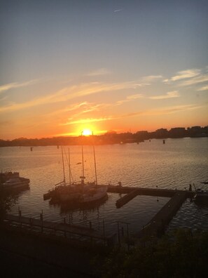 Ein Sonnenuntergang über ruhigem Wasser, mit Booten an einem Steg.