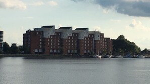 Un edificio de varios pisos con techo plano y fachada uniforme, ubicado junto al agua.