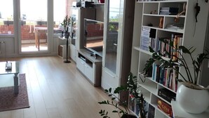 Amplia sala de estar con televisor grande, estanterías y plantas en macetas.