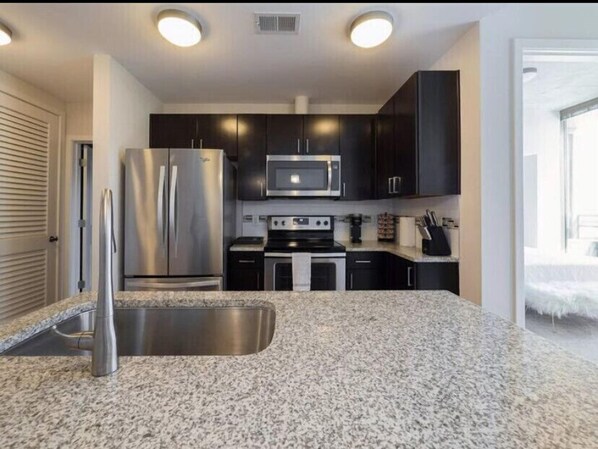 Fully equipped kitchen with a refrigerator, microwave, stove, and sink.