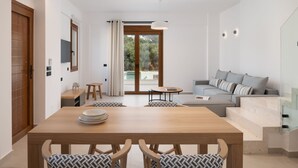 A modern living room with a wooden dining table, sofa, and a glass staircase. - De.Light Boutique Villa I, close to Rethymno (Atsipopoulo)