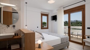 A modern bedroom with a large bed, a wooden vanity, a round mirror, a TV, and a balcony with a view of the landscape. - De.Light Boutique Villa I, close to Rethymno (Atsipopoulo)