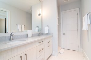 Une salle de bain moderne avec un grand miroir, deux lavabos et une douche à l’italienne.