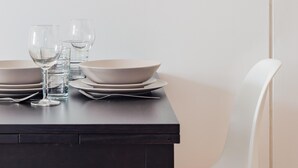 Un tavolo da pranzo con piatti, bicchieri e un bicchiere da vino, su uno sfondo neutro.